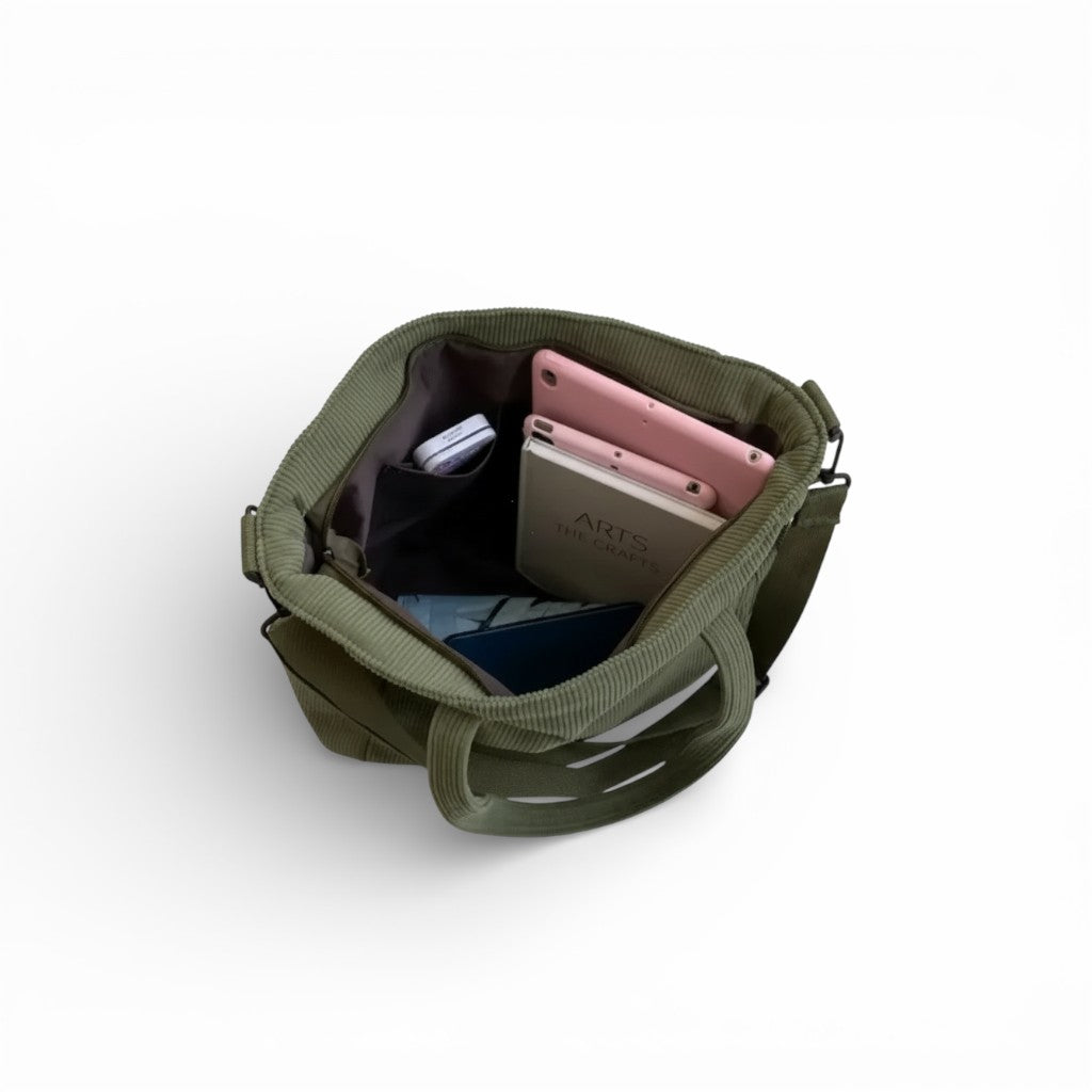 Green tote bag with electronic devices inside on a white background