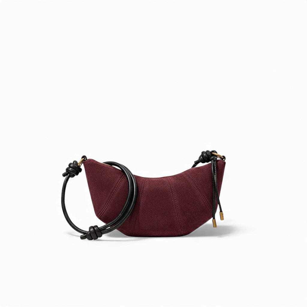 Burgundy handbag with black strap on a white background